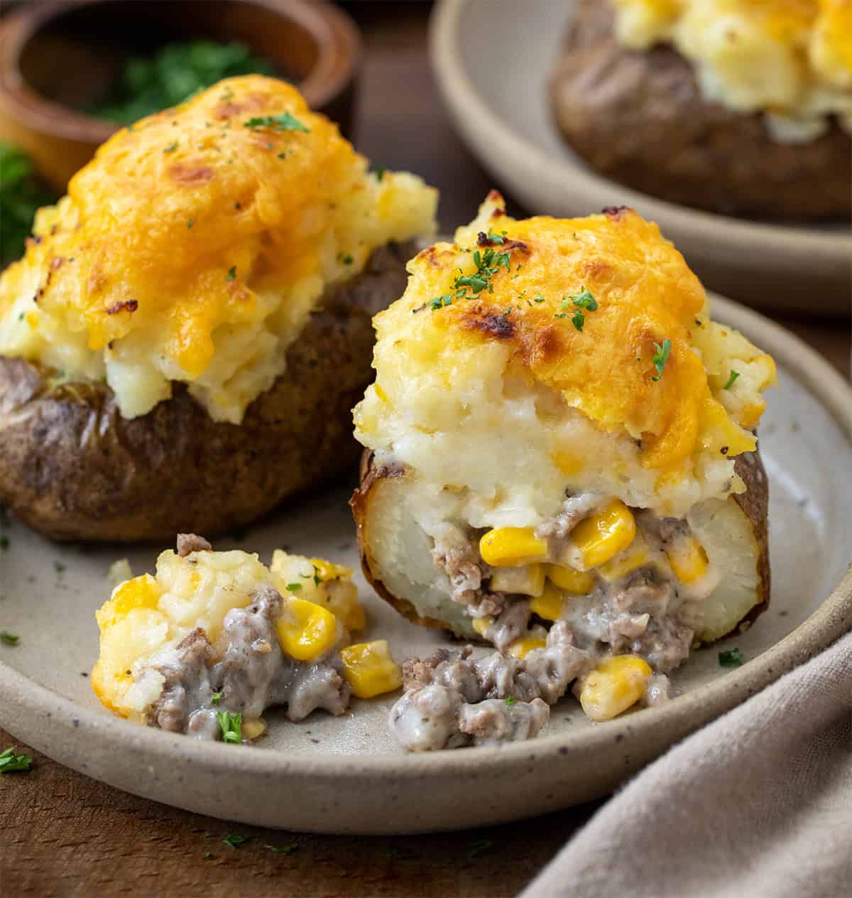 Two Shepherd's Pie Twice Baked Potatoes on a plate with one cut in half showing inside texture.