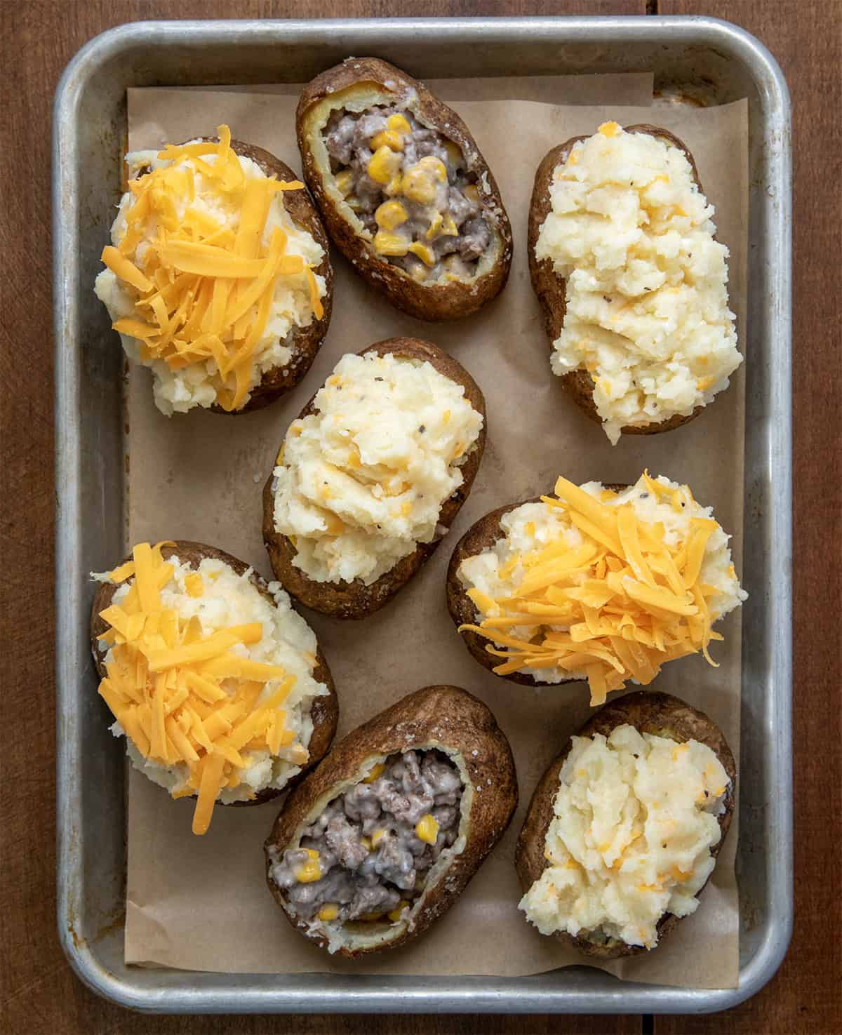 The process of baking and filling Shepherd's Pie Twice Baked Potatoes on a baking sheet from overhead.