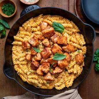Skillet of Tomato Basil Salmon Pasta on a wooden table from overhead.