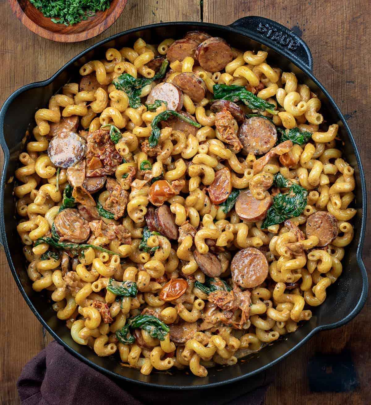 Skillet of Tuscan Sausage Pasta on a wooden table from overhead.
