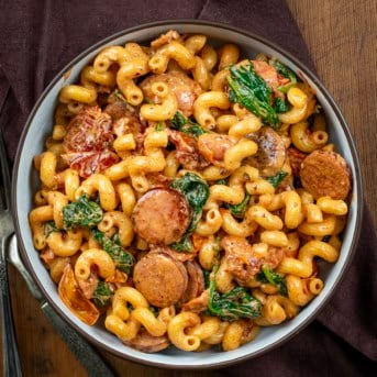 Bowl of Tuscan Sausage Pasta on a wooden table from overhead.