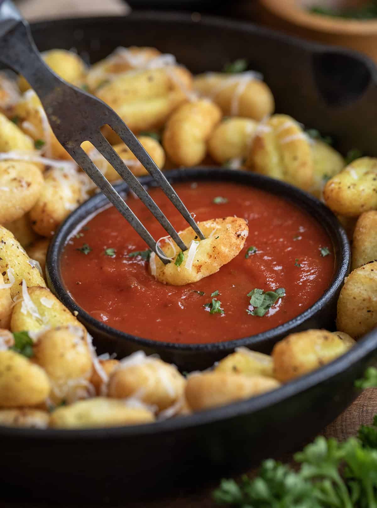 Fork dipping a piece of fried gnocchi into marinara.