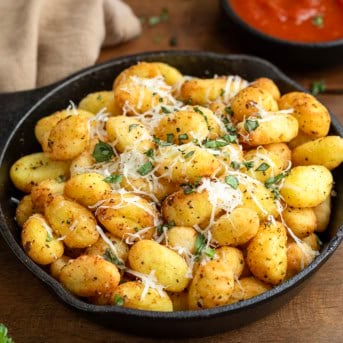 Skillet of Gnocchi Bites on a wooden table.