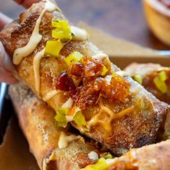Hand picking up a Bacon Jam Cheeseburger Egg Roll with bacon jam.