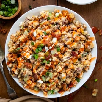 White bowl of Buffalo Roasted Potato Salad on a wooden table from overhead.