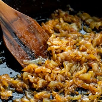 Caramelized Onions in a skillet with a wooden spoon close up.