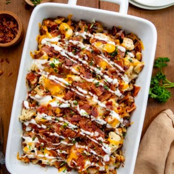White casserole dish filled with Chicken Bacon Ranch Roasted Potato Bake on a wooden table from overhead.