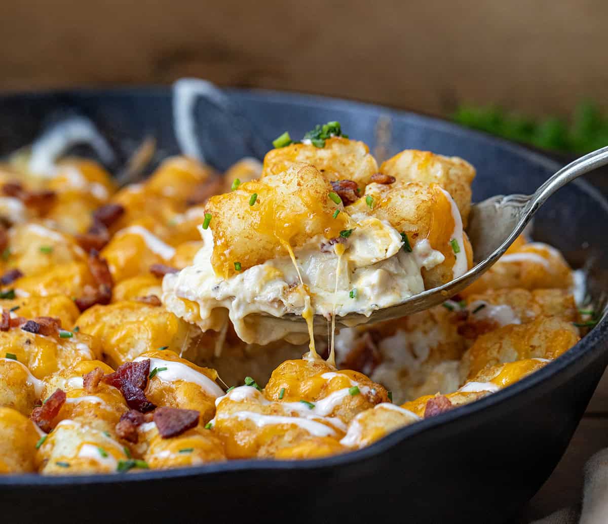 Spoonful of Chicken Bacon Ranch Tater Tot Casserole being held over the pan close up.