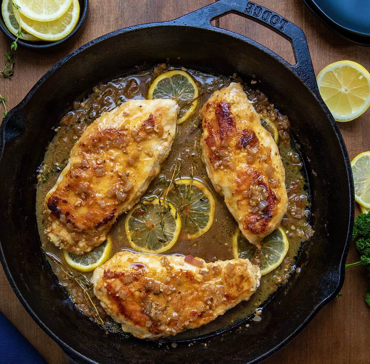Chicken Breasts with Lemon in a black skillet on a wooden table from overhead.