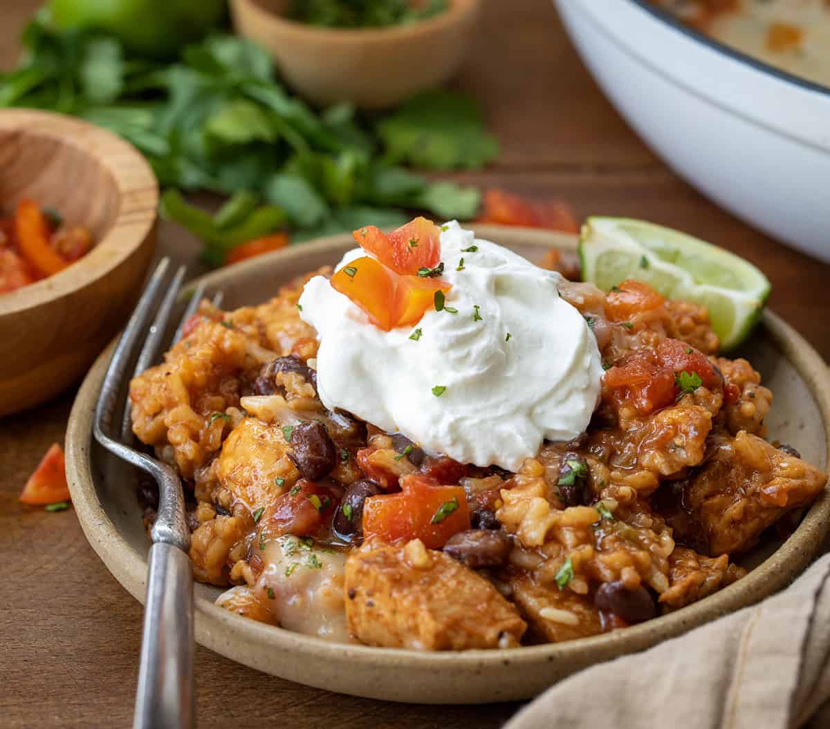 Plate of Cheesy Chicken Taco Rice with a dollop of sour cream on top.
