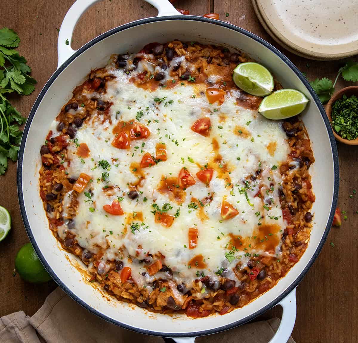 Enjoy a cozy meal with Cheesy Chicken Taco Rice, a flavorful one-pan dish with chicken, black beans, and melty cheese! Skillet of Cheesy Chicken Taco Rice on a wooden table from overhead.