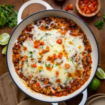 Skillet of Cheesy Chicken Taco Rice on a wooden table from overhead.