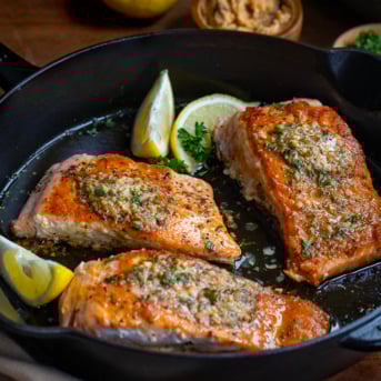 Three pieces of Cowboy Butter Salmon in a skillet.