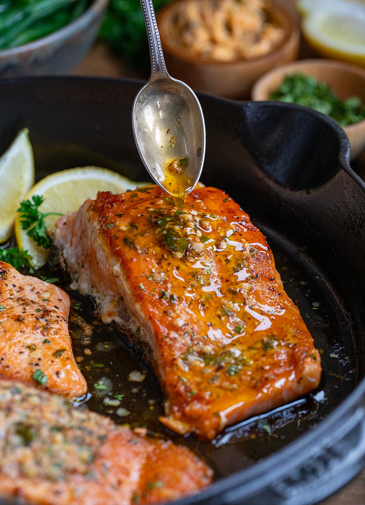 Drizzling cowboy butter over cooked salmon.
