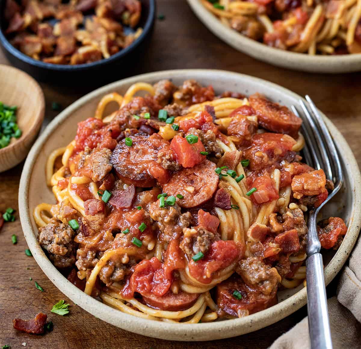Plates of One Pot Cowboy Spaghetti on a wooden table.