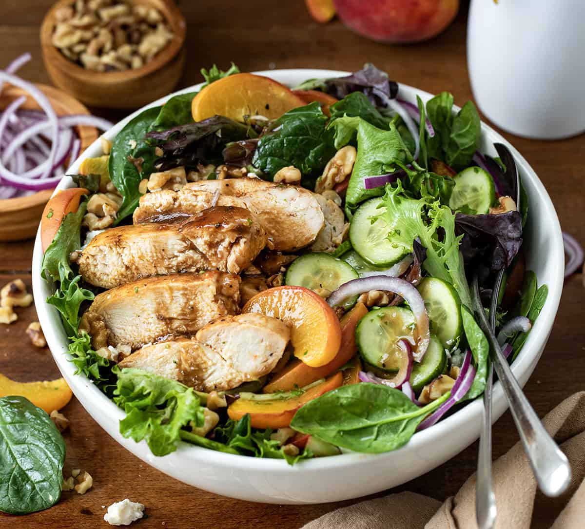 Roasted Peach Chicken Salad in a white bowl on a wooden table.