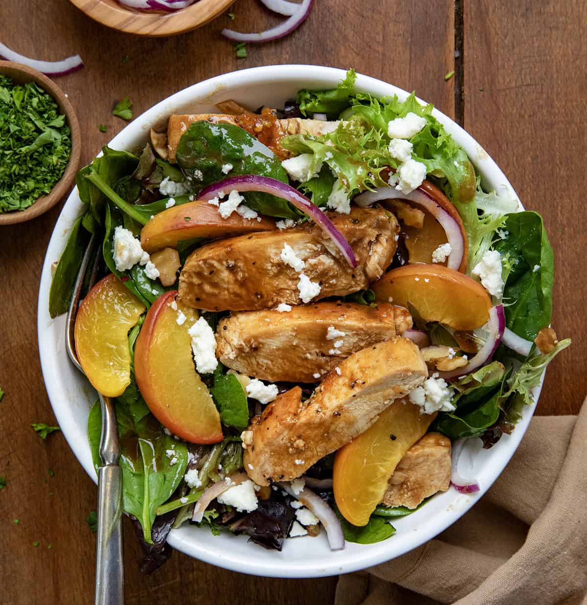 Single serving of Roasted Peach Chicken Salad on a wooden table from overhead.