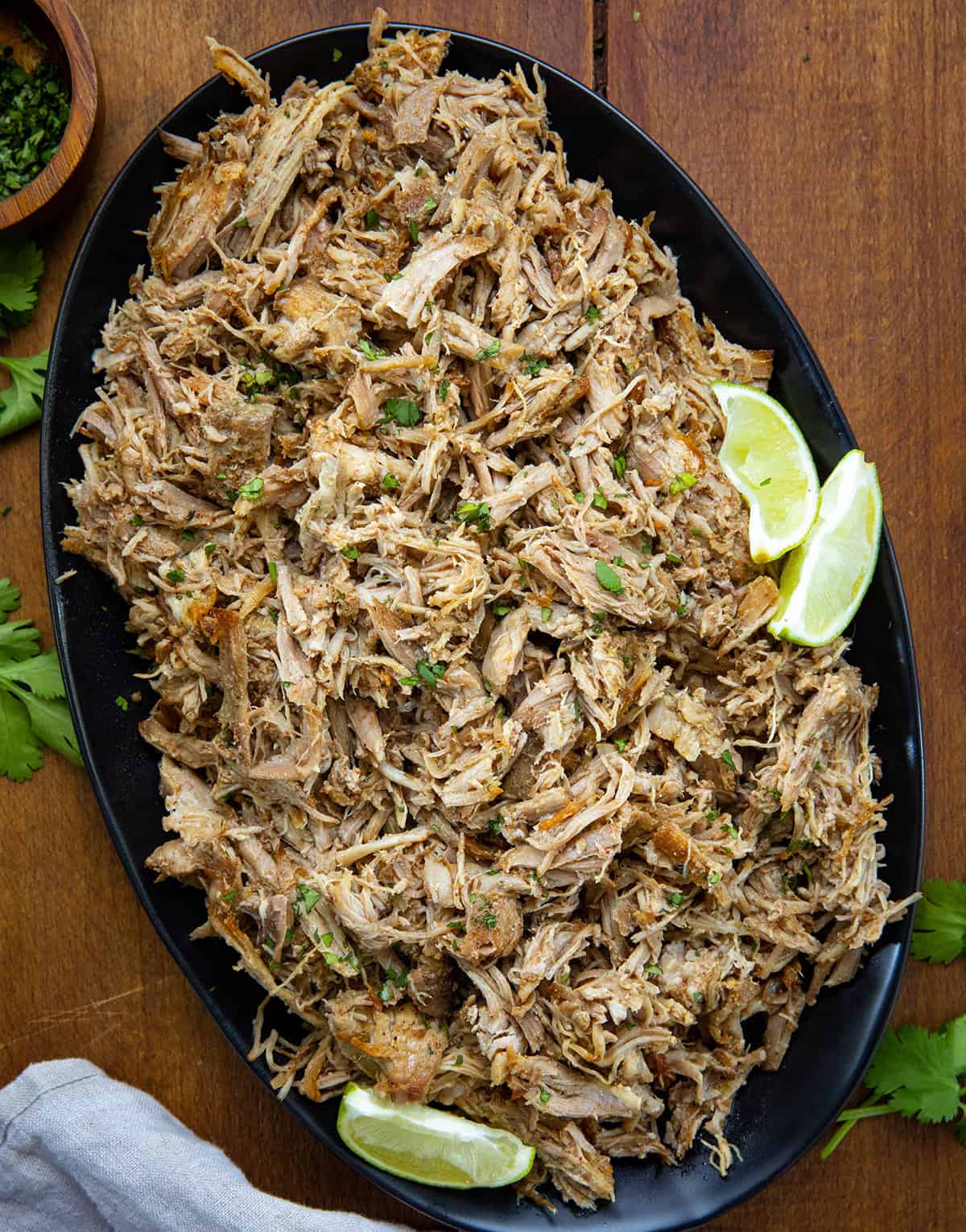 When I want something easy but full of flavor, this Slow Cooker Carnitas recipe is one of my go-to dinners! The pork cooks low and slow until it’s fall-apart tender, then gets broiled for crispy edges, just the way carnitas should be! Platter of Slow Cooker Carnitas on a wooden table from overhead.
