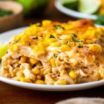 Close up of Street Corn Chicken Enchiladas on a white plate.
