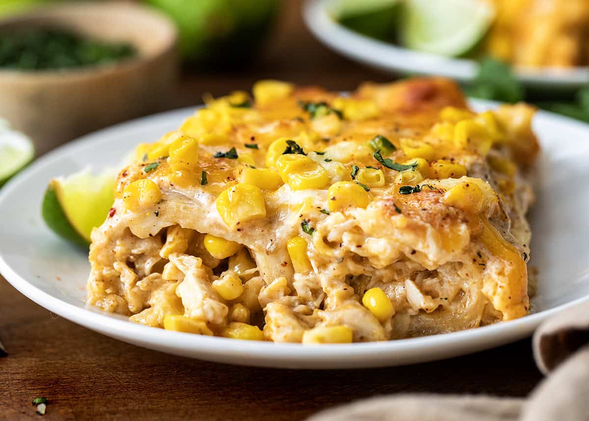 Close up of Street Corn Chicken Enchiladas on a white plate.