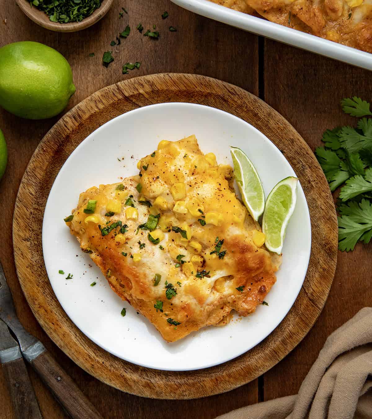 Halved Street Corn Chicken Enchiladas on a white plate on a wooden table from overhead.
