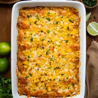 Pan of Street Corn Chicken Enchiladas on a wooden table from overhead.