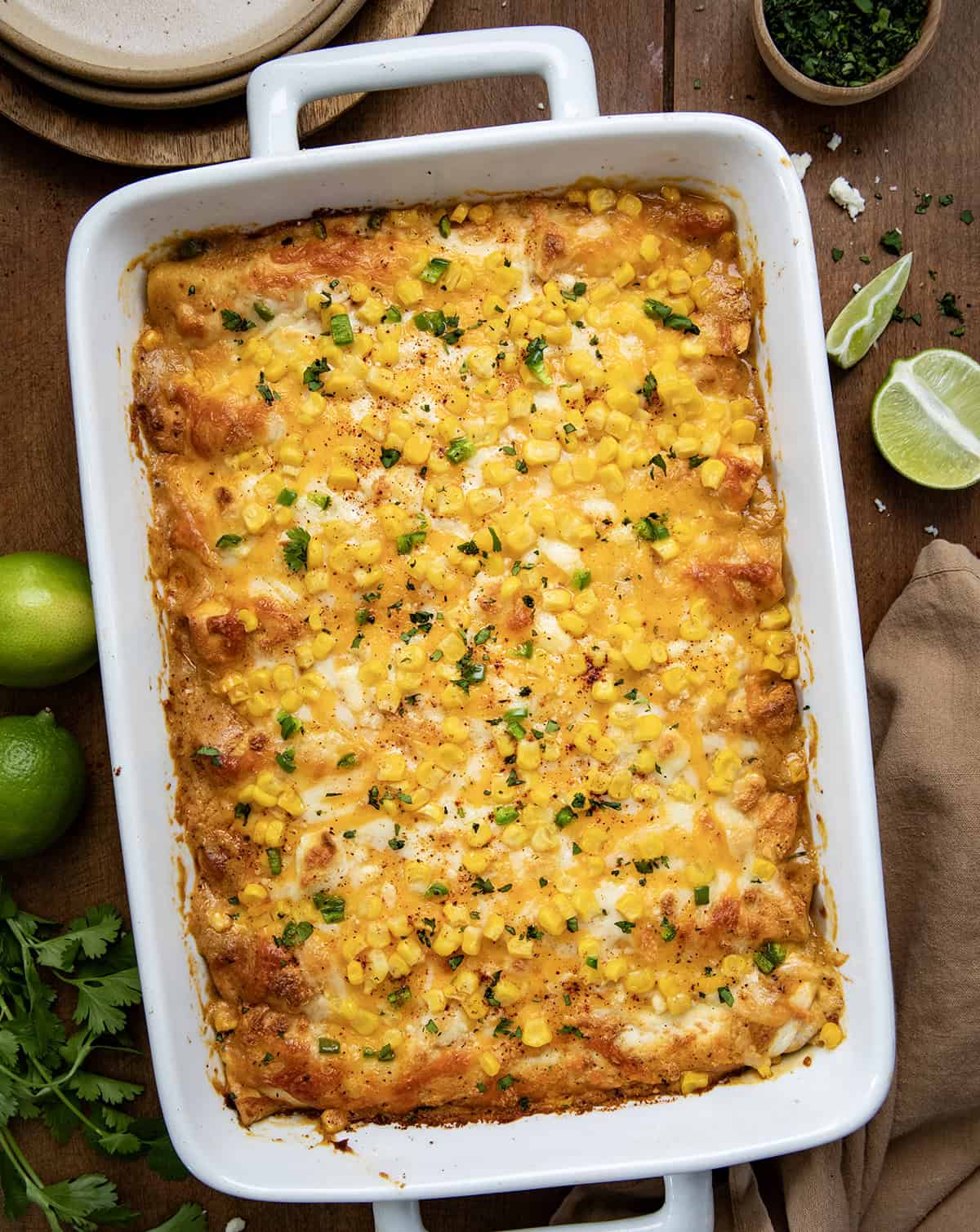 Pan of Street Corn Chicken Enchiladas on a wooden table from overhead.