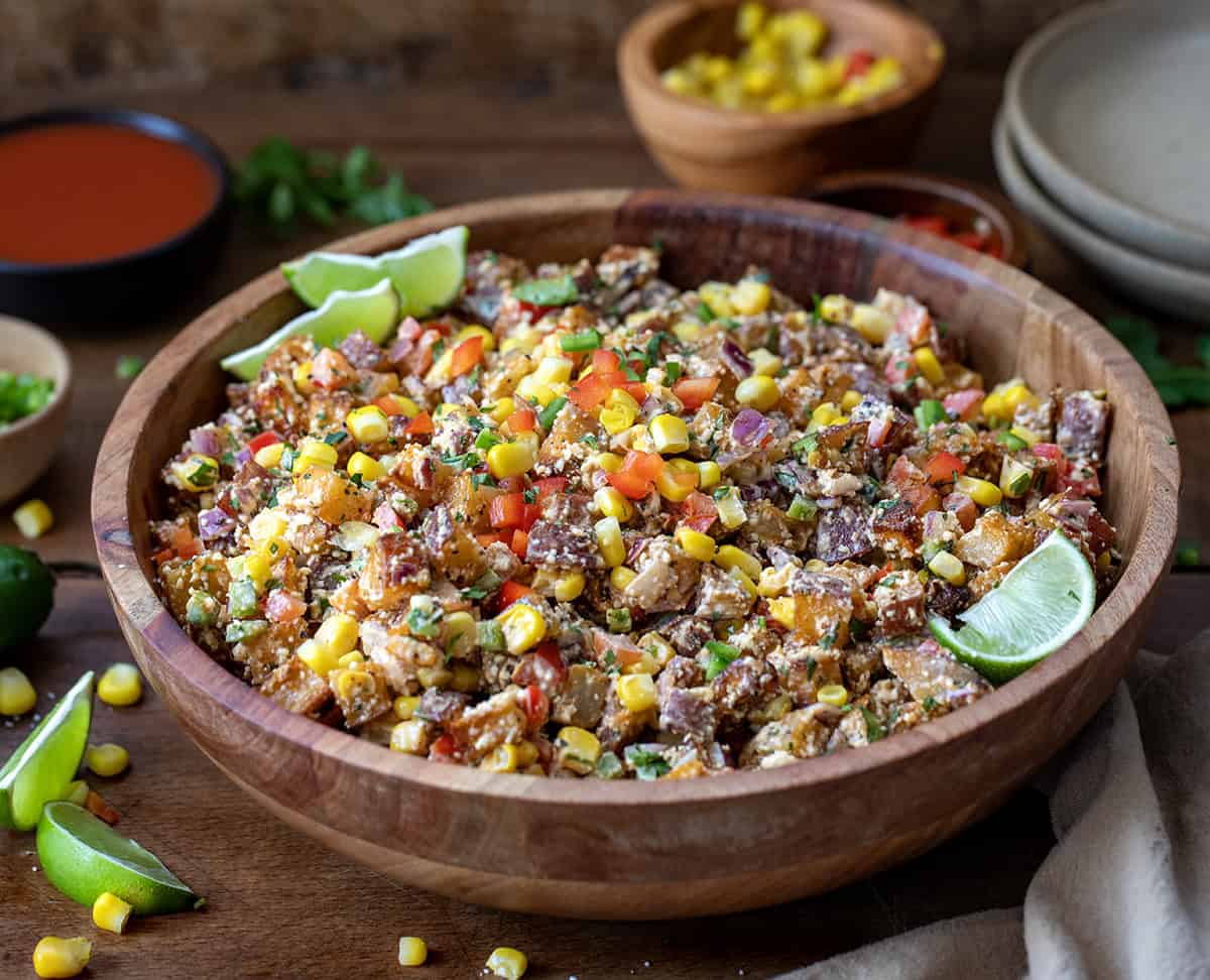 Wooden bowl filled with Street Corn Roasted Potato Salad on a wooden table.