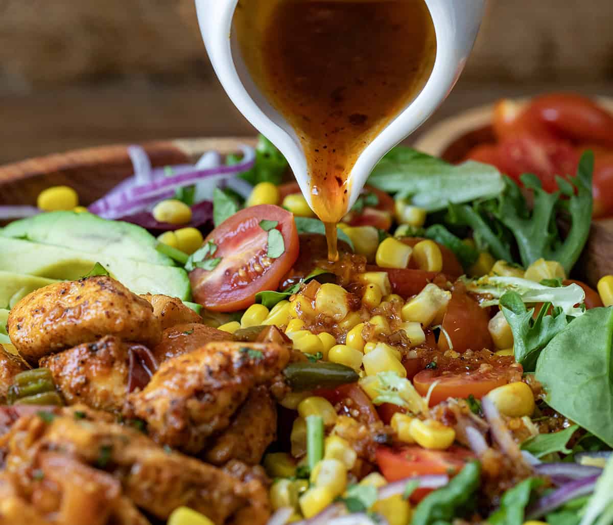 Pouring dressing over Sweet and Spicy Chicken Peach Salad.