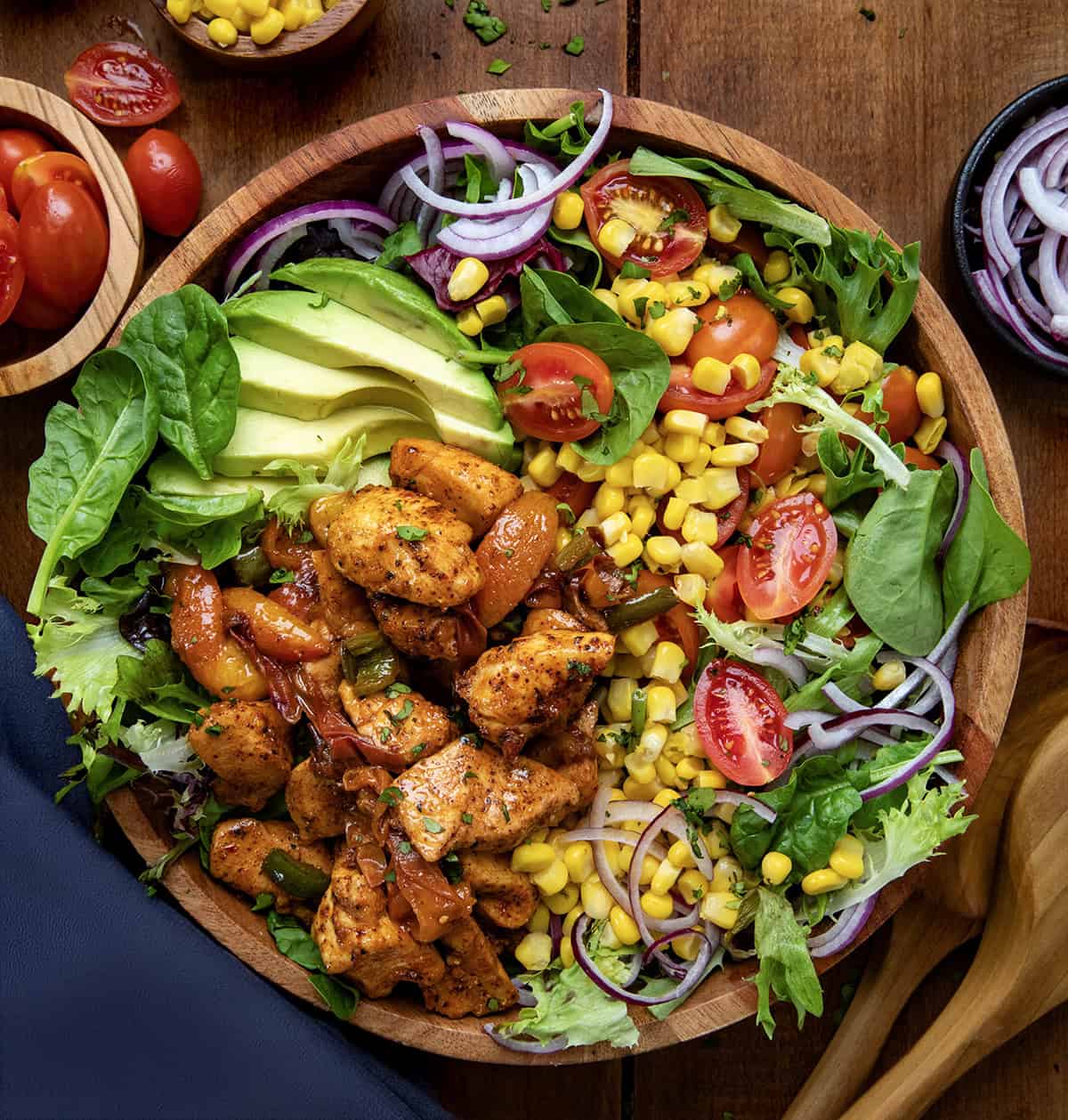 Bowl of Sweet and Spicy Chicken Peach Salad on a wooden table from overhead.