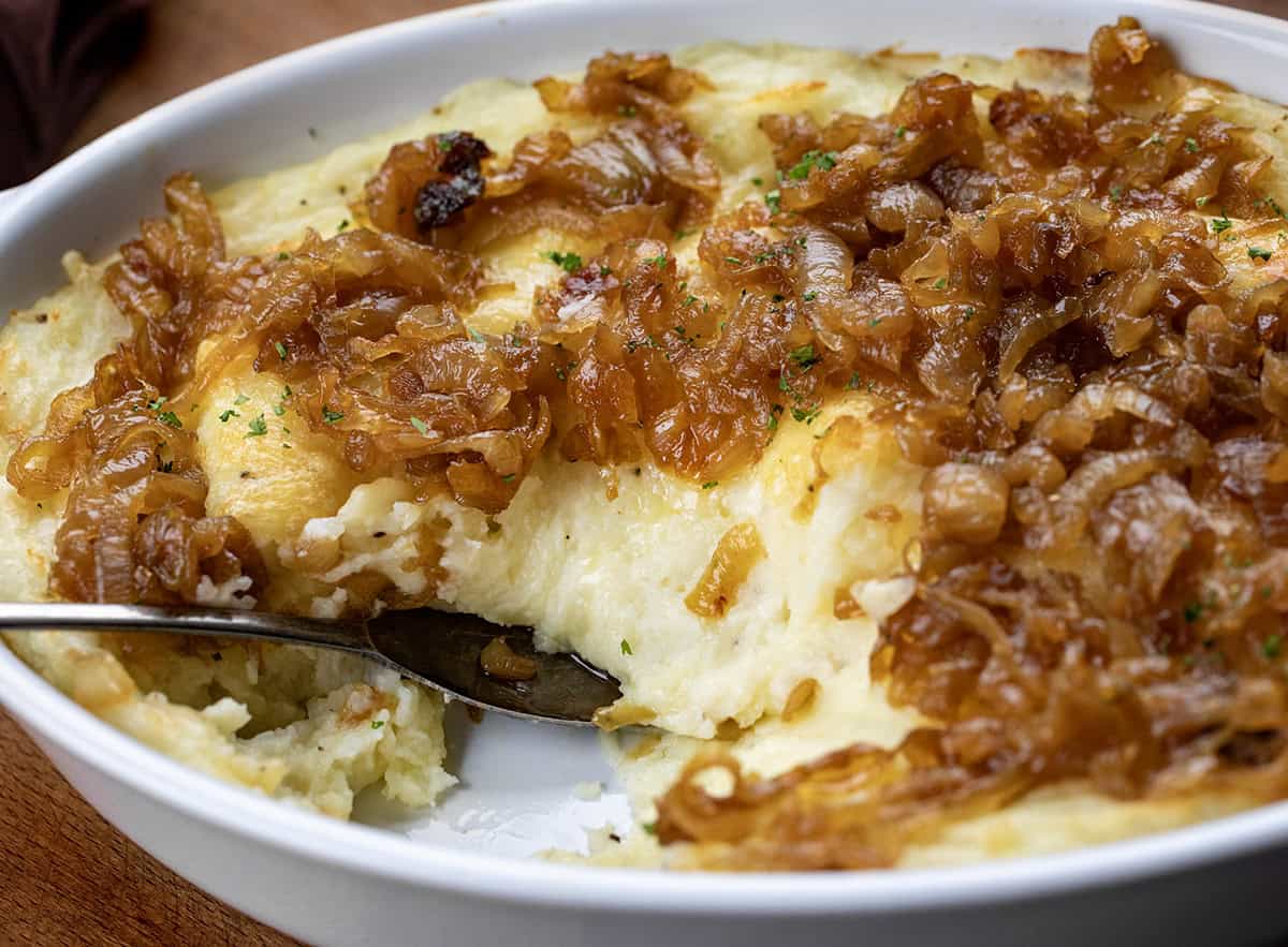 Pan of Twice Baked French Onion Mashed Potatoes with some removed showing the creamy potatoes.