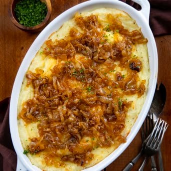 Dish of Twice Baked French Onion Mashed Potatoes on a wooden table from overhead.