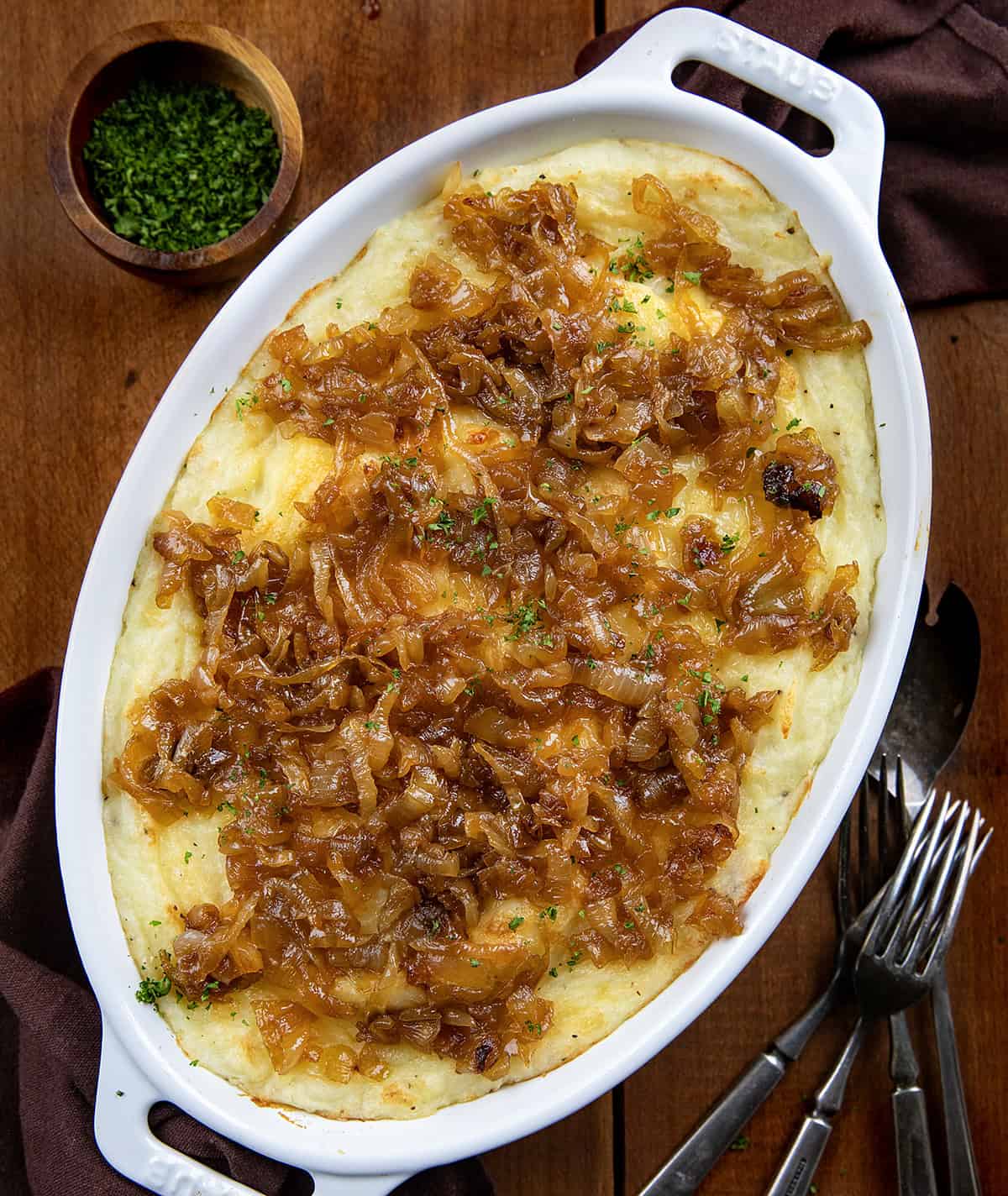 Dish of Twice Baked French Onion Mashed Potatoes on a wooden table from overhead.