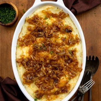White pan of Twice Baked French Onion Mashed Potatoes on a wooden table from overhead.