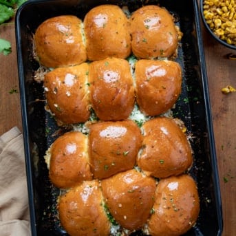 Carnitas Street Corn Sliders in a black pan on a wooden table from overhead.
