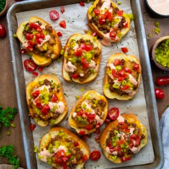 Cheeseburger Garlic Bread on a sheet pan on a wooden table from overhead.