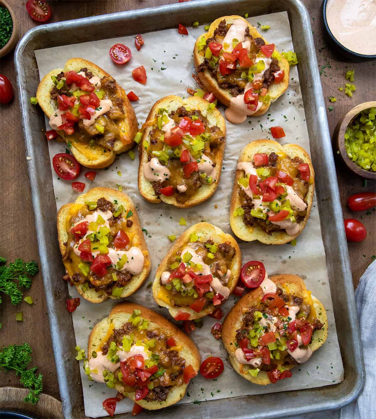 Cheeseburger Garlic Bread on a sheet pan on a wooden table from overhead.