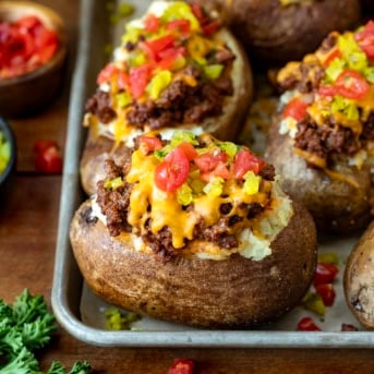 Cheeseburger Twice Baked Potatoes on a sheet pan on a wooden table.