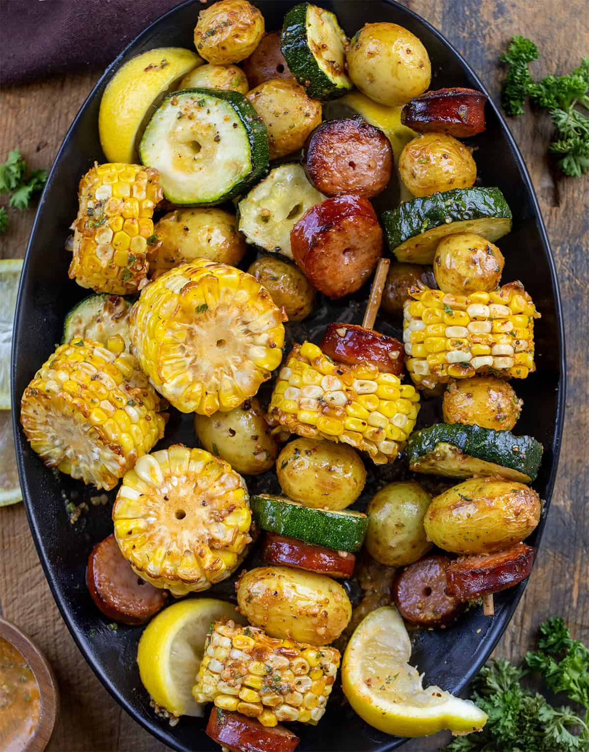 Platter of Cowboy Butter Kielbasa and Potato Skewers with some of the vegetables removed from the skewers.