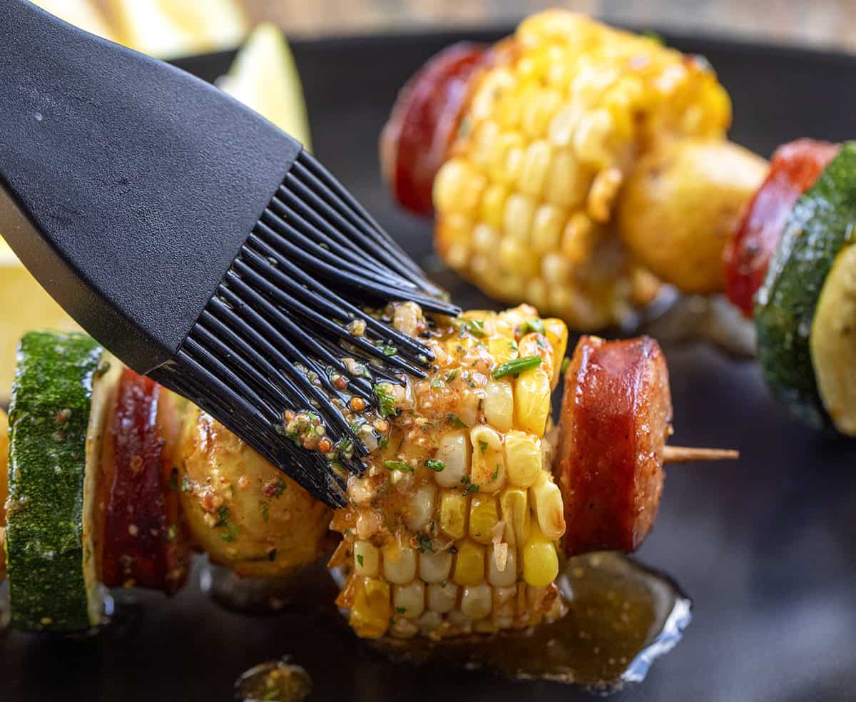 Brushing cowboy butter over corn on the cob.