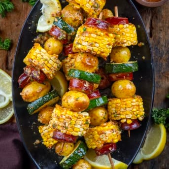 Platter of Cowboy Butter Kielbasa and Potato Skewers on a wooden table from overhead.