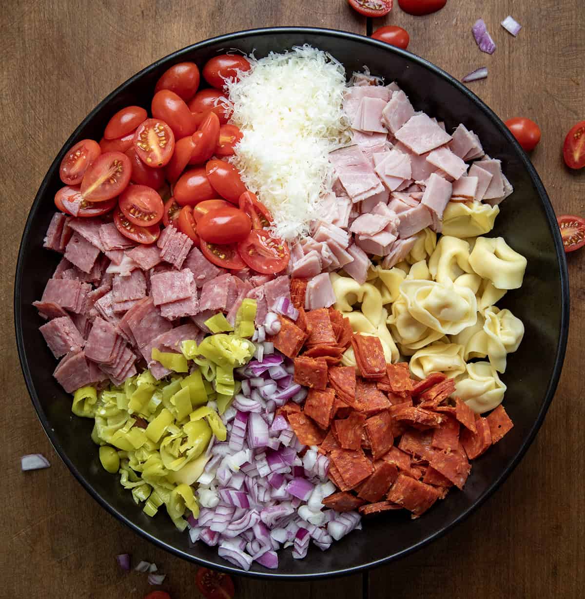 Raw ingredients for Italian Grinder Tortellini Salad in a bowl before being mixed so each section of food is separate.