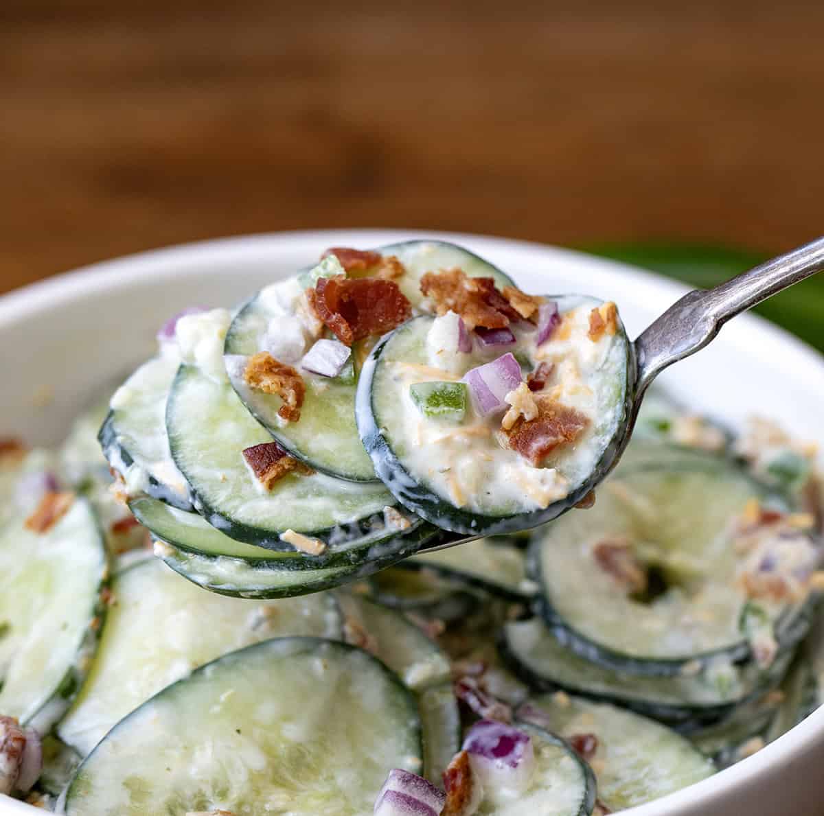 Spoonful of Jalapeno Popper Cucumber Salad being held above the bowl.
