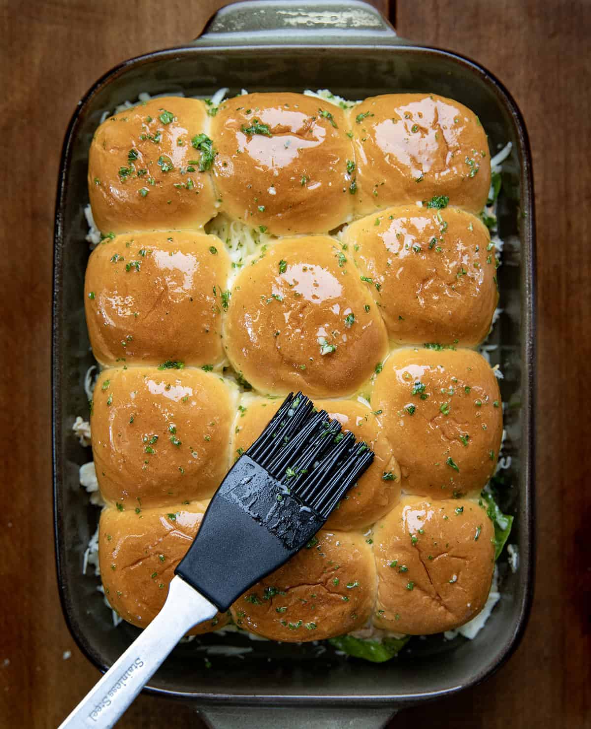 Brushing garlic butter over Marry Me Chicken Sliders.