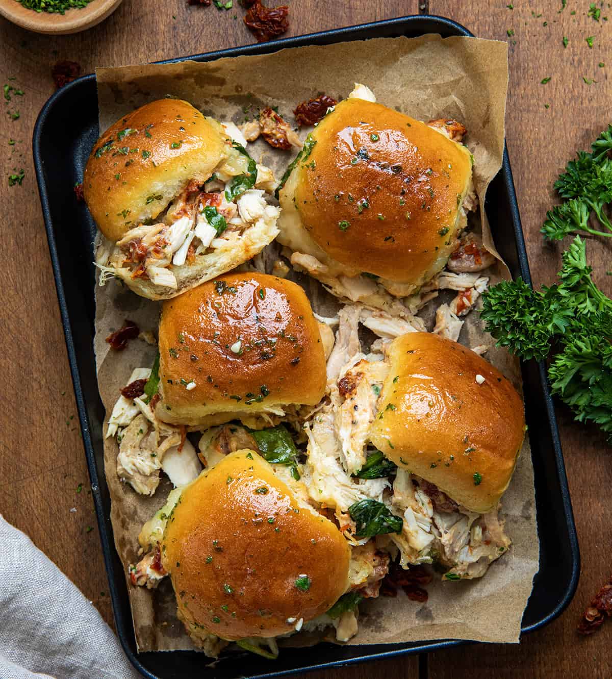 Marry Me Chicken Sliders in a pan on a wooden table from overhead.