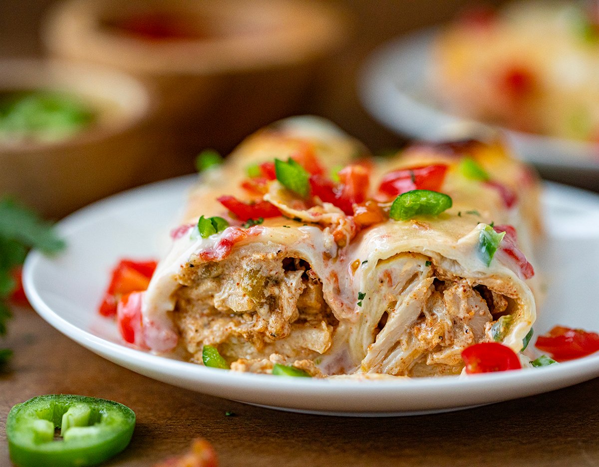 Cut Queso Enchiladas on a plate on a wooden table.