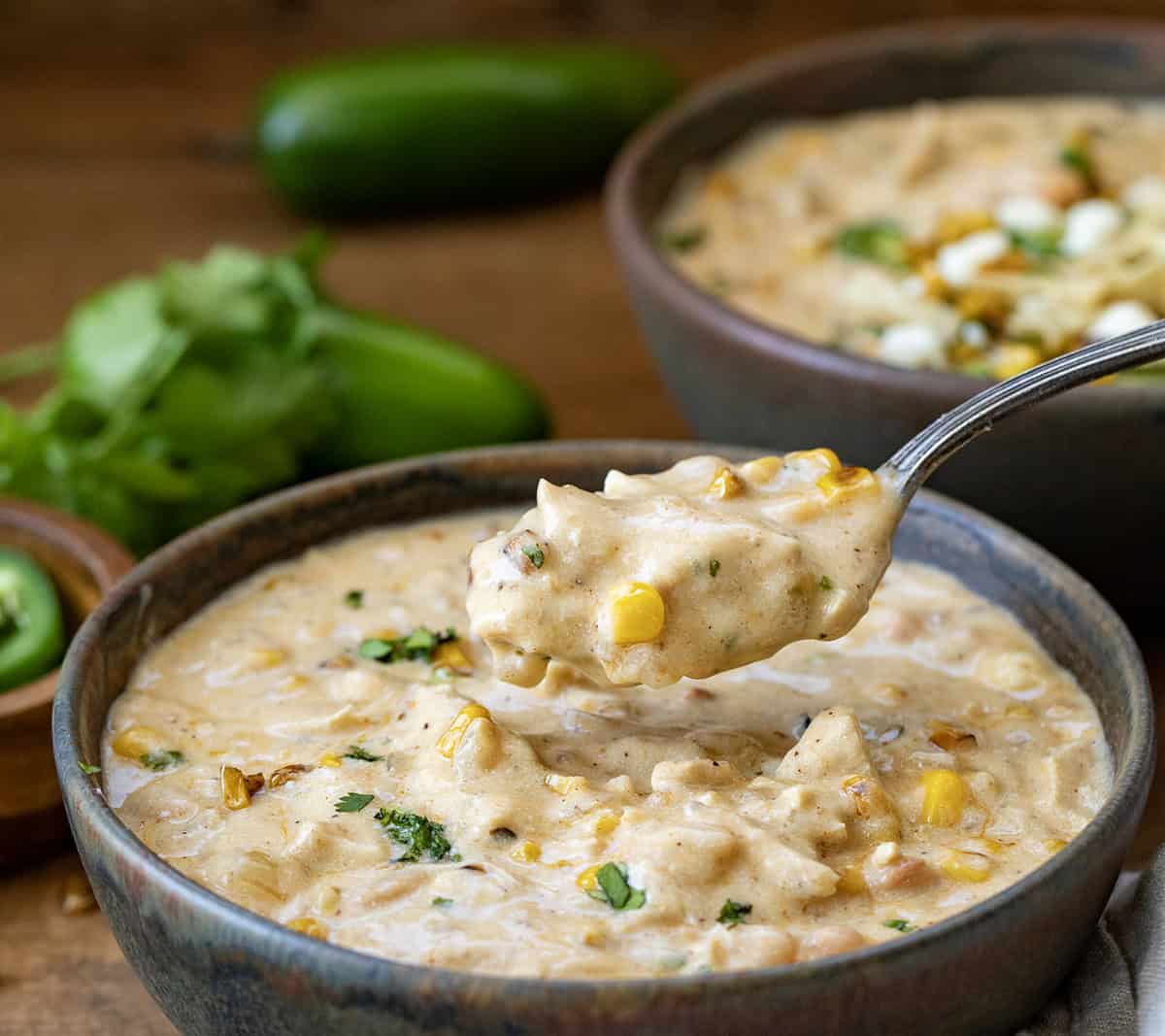 Spoonful of Street Corn White Chicken Chili being held above a bowlful.