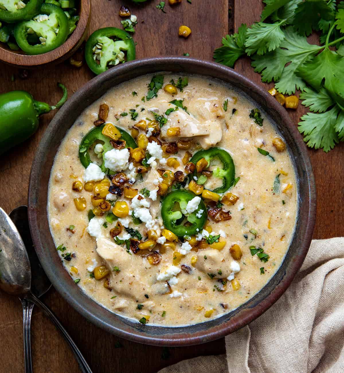 Bowl of Street Corn White Chicken Chili on a wooden table from overhead.