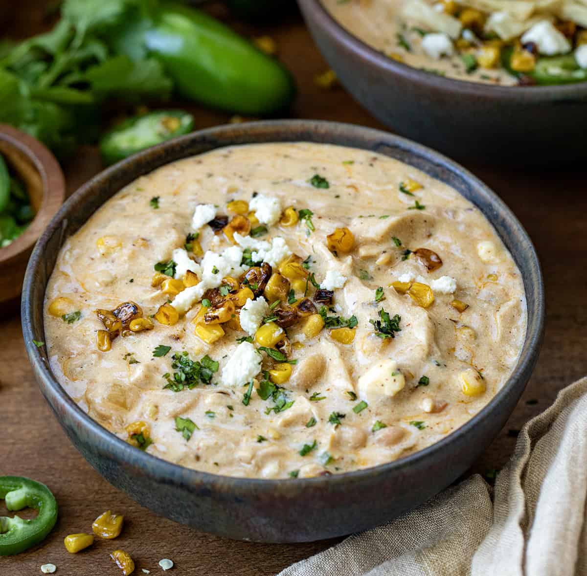 Bowl of Street Corn White Chicken Chili on a wooden table close up.