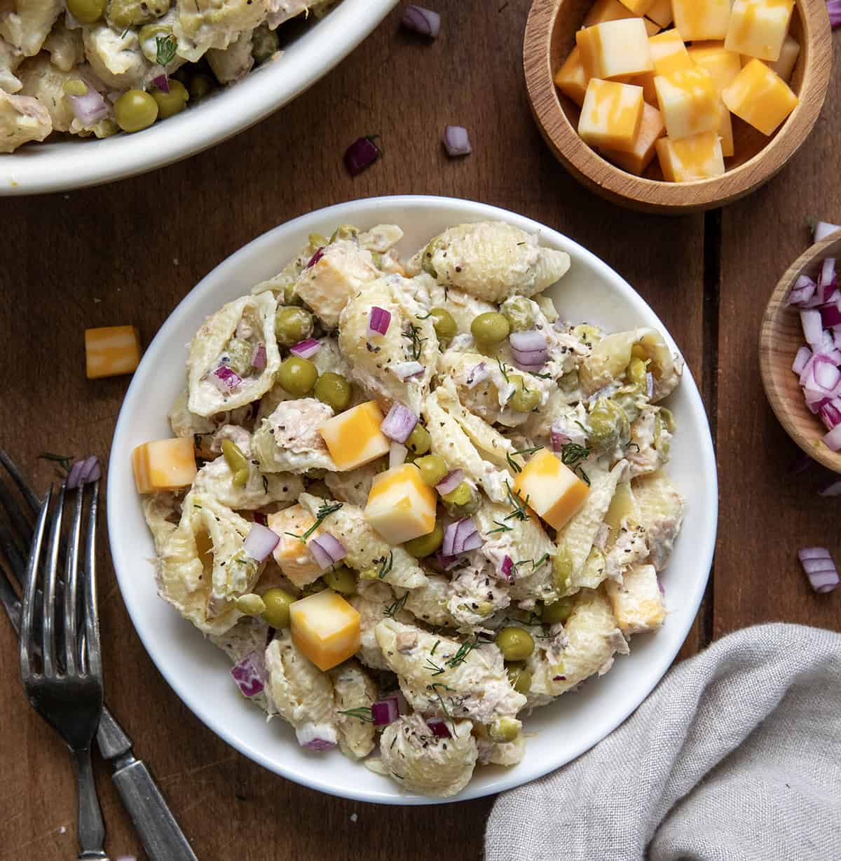 Plate of Tuna Pasta Salad next to a big bowl on a wooden table from overhead.